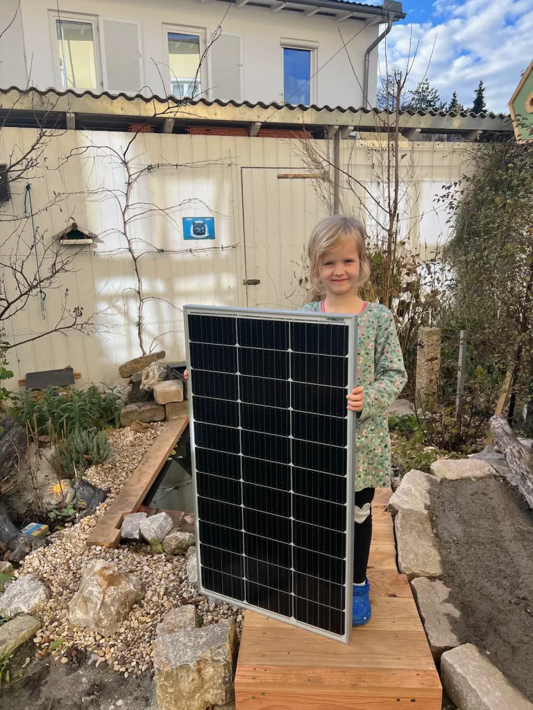 Mädchen in Naturgarten mit einer Solarzelle