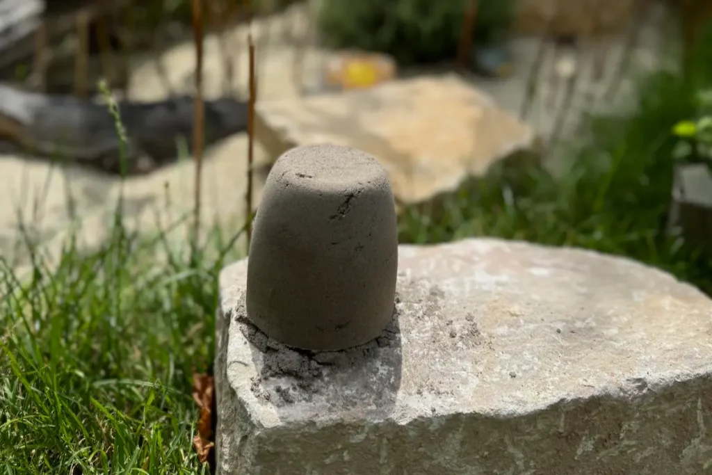 Mit einem Becher geformter Sandhaufen auf einem Felsen / Stein