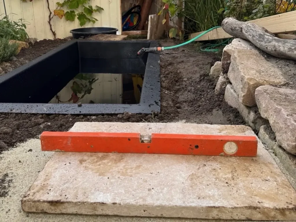 Wasserwaage auf einem Terrassenstein, der als Fundament für einen Steg dient