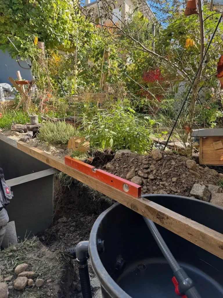 Kontrolle ob Mini-Teich waagrecht eingebaut wurde mit Wasserwaage und Holzlatte