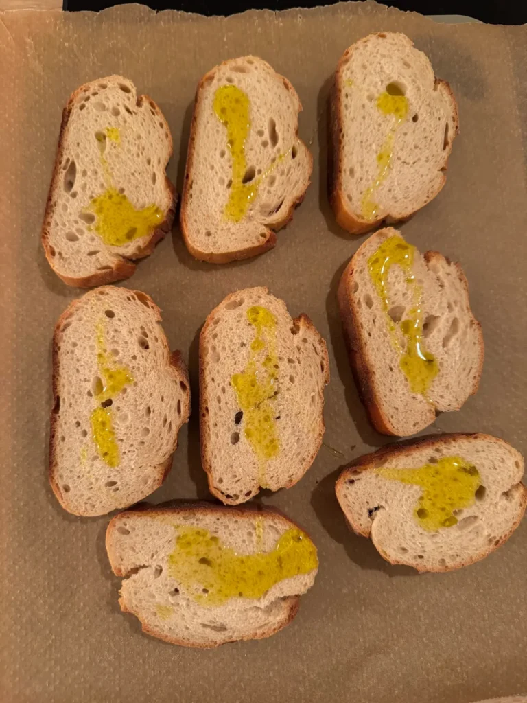 Brotscheiben auf einem Backblech mit Olivenöl beträufelt