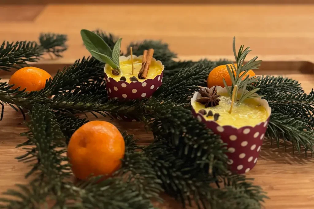 Zwei Butterkerzen und Tannenzweigen, sowie Mandarinen auf dem Tisch