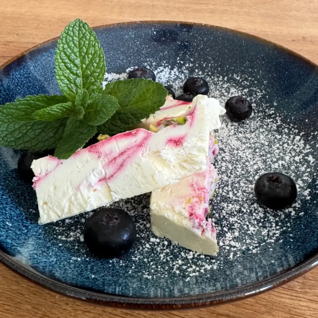 Parfait auf Teller angerichtet mit Minze und Blaubeeren.