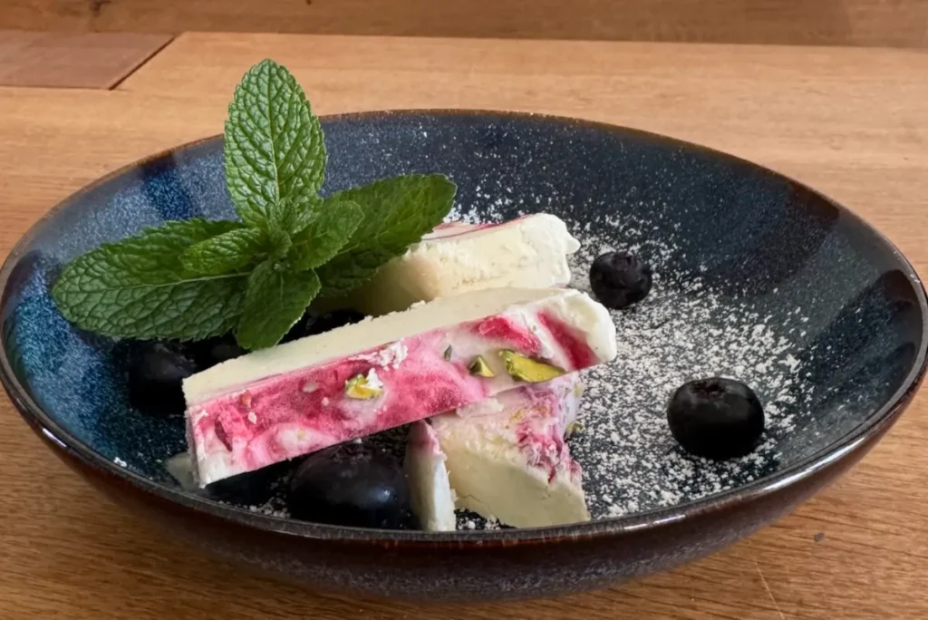 Parfait auf Teller angerichtet mit Minze und Blaubeeren.