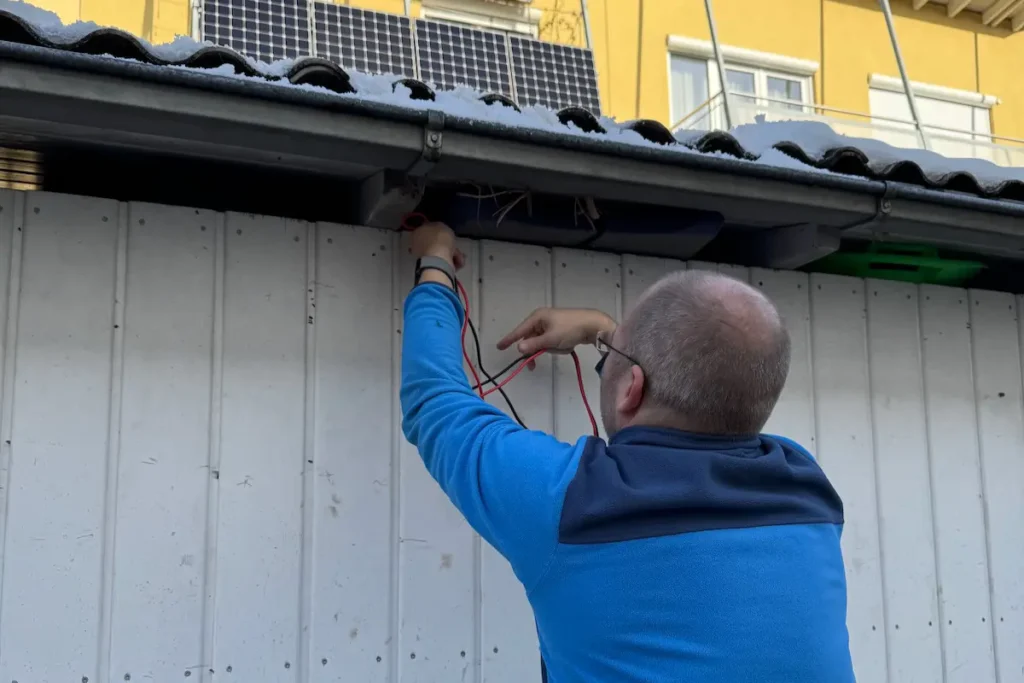 Mann führt Anschlusskabeln in ein Gartenhaus