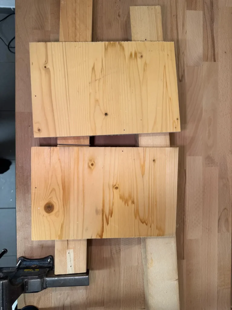 Seitenteile aus Holz liegen auf einer Werkbank.