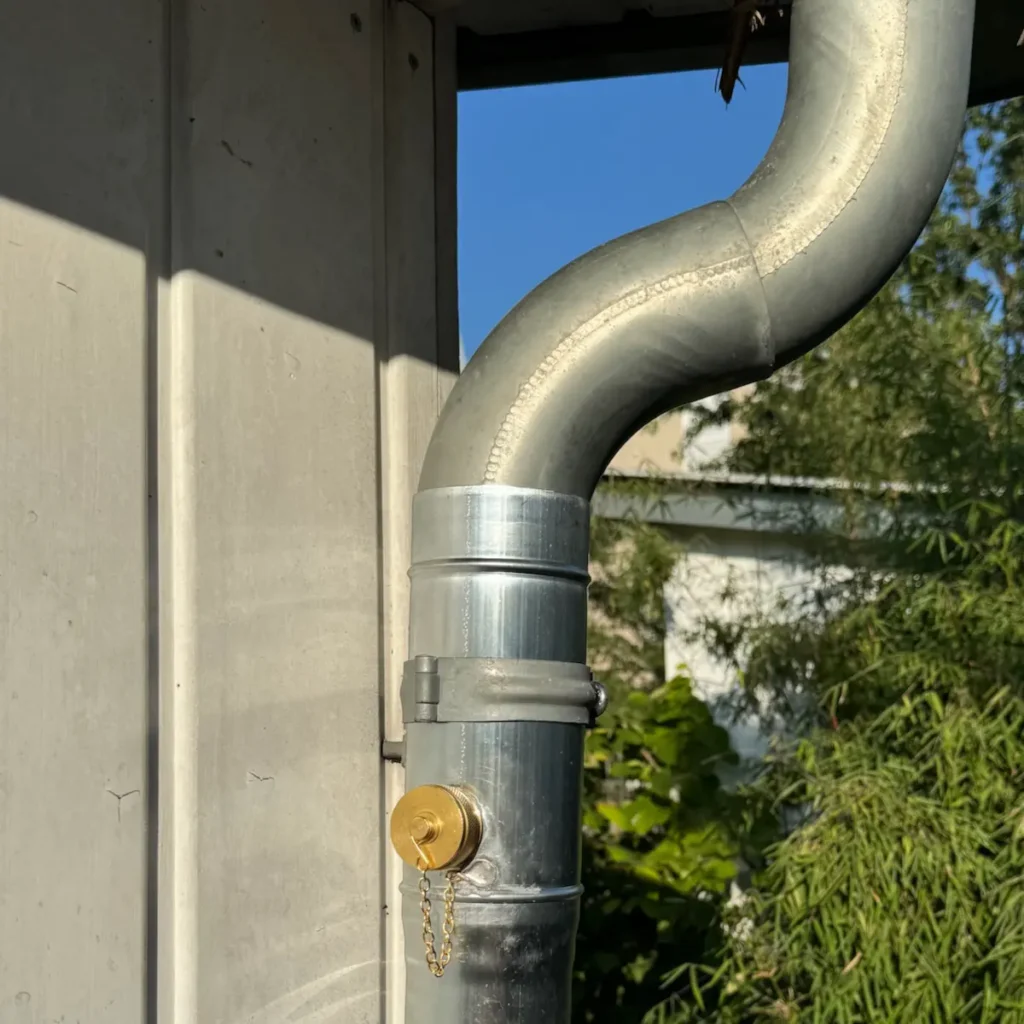 Regenrinne mit Regensammler an einem Gartenhaus.