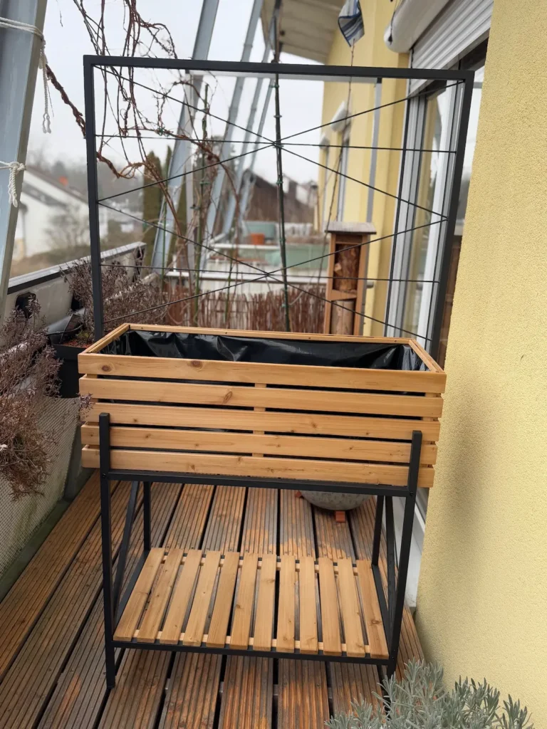 Ein Hochbeet aus Holz und Stahl steht auf einem Balkon.