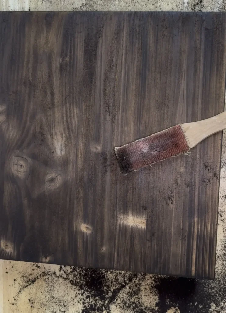 Verkohlter Holzdeckel und Messingbürste.